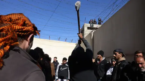 EPA A man uses a hammer while searching secret cells containing prisoners in Saydnaya prison, north of Damascus, Syria (December 9, 2024).