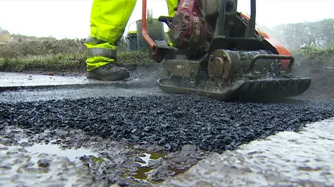 A Nottinghamshire County Council worker putting in a hot mix asphalt repair