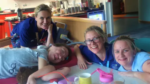 Three hospice support staff members are sitting next to a patient. 