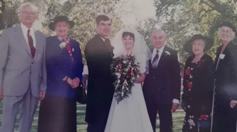 Wedding picture of a group of people with the bride and groom at the centre