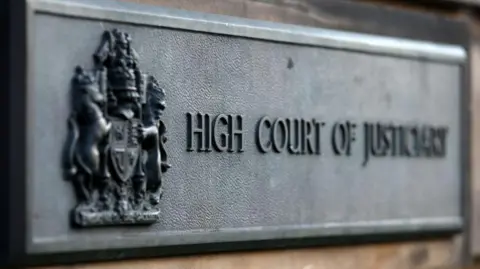 PA Media Grey court sign with words 'High Court of Justiciary' in block capitals at the High Court in Edinburgh