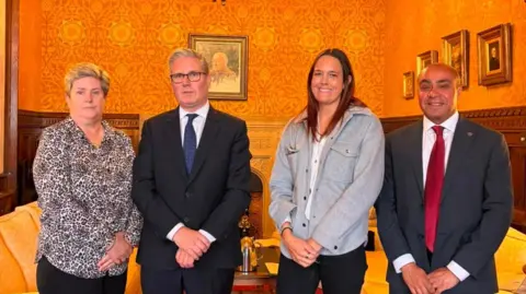 Conner Agius Angie Long stands alongside Keir Starmer, David Burton-Sampson and Natalie Atmos. They are standing in a brightly lit drawing room. 