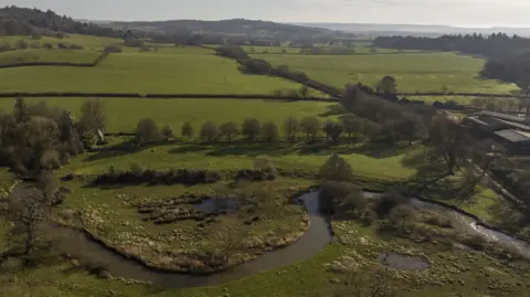 National Trust Images James Beck A landscape of fields and trees with a winding river in the foreground