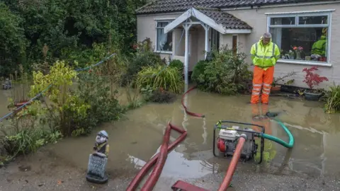 Norfolk Fire Museum A pump and a volunteer in the garden of a home in Attleborough.
