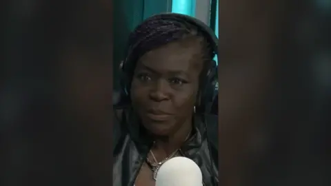 Dame Dr Maggie Aderin-Pocock in front of a microphone in the BBC 5 Live studio