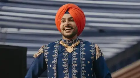 Rajvir Jawanda/Instagram A photo of Rajvir Jawanda wearing an orange turban and blue and gold kurta