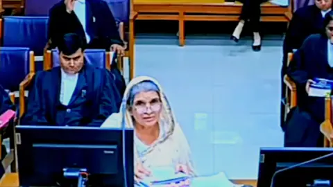 When India professor used chemistry as defence in murder trial but failed A woman wearing a white sari and flanked by lawyers deposing in a court in the Indian state of Madhya Pradesh