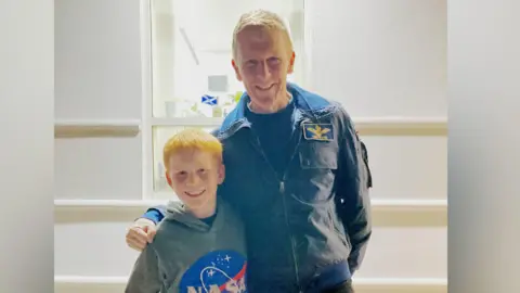 PA Media Efan standing with Tim Peak. Efan is wearing a Nasa top. Tim is wearing a blue jacket.