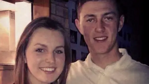 supplied A young couple pose together smiling broadly.