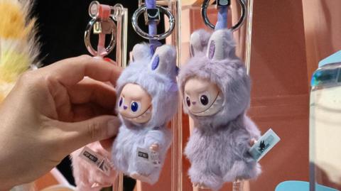 Customers look at mini Labubu toys at a Pop Mart store in Beijing, China