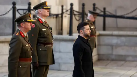 Reuters Ukrainian President Volodymyr Zelenskiy inspects a guard of honour by the Irish Army at Government Buildings during an Irish State visit, in Dublin, Ireland. He is dressed in black clothing with two Irish guards behind him.