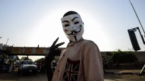 Getty Images A Sudanese protester wears a Guy Fawkes mask outside the army headquarters in Khartoum on May 6, 2019.