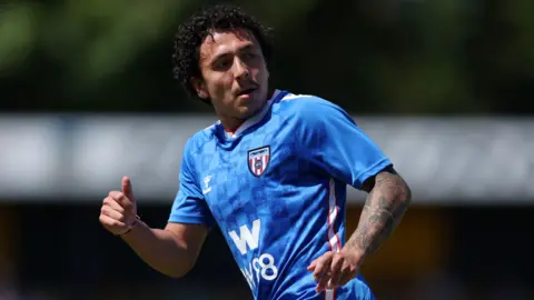George Wood/Getty Ian Poveda is running during a match. He has black curly hair and is wearing a blue Sunderland away kit. He has tattoos on his arm.