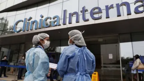EPA Health personnel stand outside of a private clinic after the last-minute agreement reached between the Government and private clinics to reduce health care prices during the pandemic, in Lima, Peru, 25 June 2020