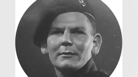 Laurence Neal A black and white photo of Alfred Edward Thomas (Eddie) Annetts in Army uniform during World War Two. He has a beret on his head and very short hair. His chin is up and he is looking into the distance. The photo has been cut into a round shape to fit a locket. 