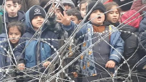 Reuters Migrant children gather near the fence on the Poland/Belarus border near Kuznica, Poland, in this video-grab released by the Polish Interior Ministry, November 11, 2021