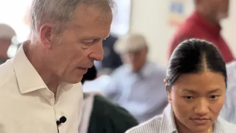Matt Rodda MP is standing alongside Pratikshya Gurung, talking and listening to a group of Gurkha veterans at their community centre in Reading. Deep in conversation. 