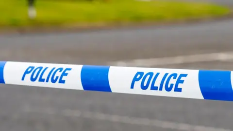 Police marker tape cordons crime scene.