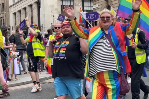 Pride marchers in Glasgow carrying banners and wearing colourful clothes 