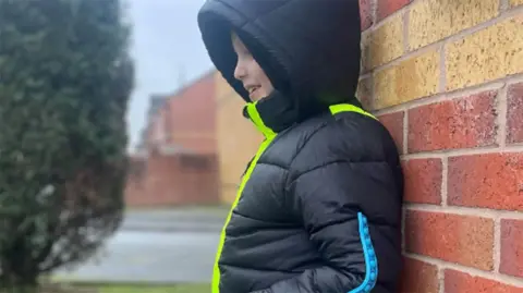 Boy wearing a hooded black jacket with luminous stripes