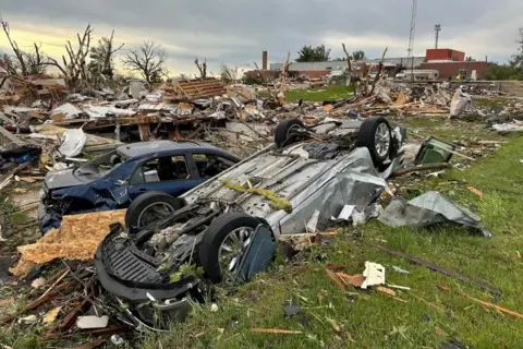 Car is flipped over and covered in debris from tornado