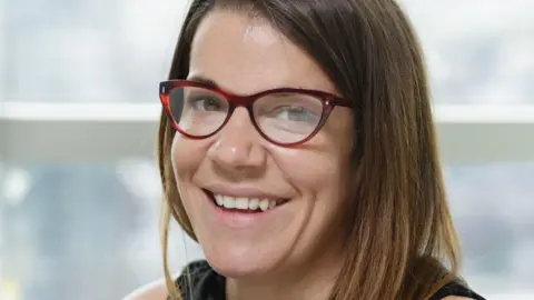 National Trading Standards Woman smiling with glasses.