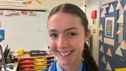 Ciara. She has brown eyes and brown hair tied back in a plait. 