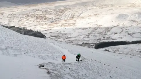 Getty Images Two walkers in the snow on Pen Y Fan in the Brecon Beacons