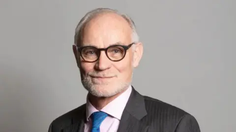 A close up head and shoulders image of Crispin Blunt