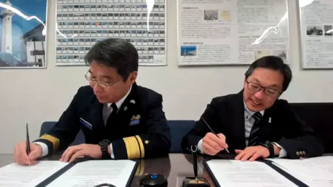 NLB Two men from the Japanese coastguard put pen to paper on a twinning agreement with a Scottish lighthouse