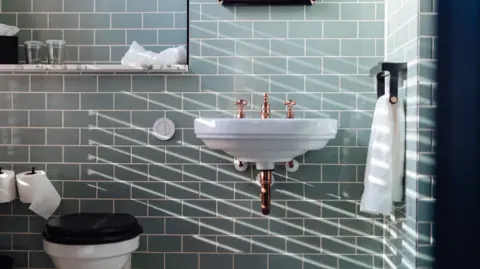 Image of bathroom fixtures including toilet and sink and arrangement of white towels