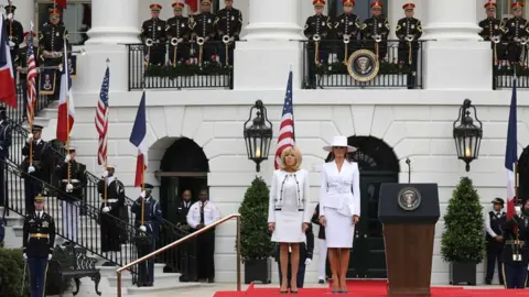 AFP French First Lady Brigitte Macron and US First Lady Melania Trump (R) stand on the podium during a state arrival ceremony at the White House in Washington DC on 24 April 2018