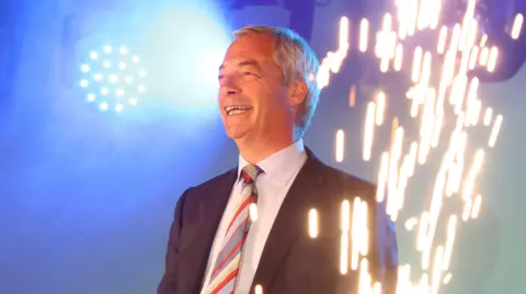 Nigel Farage pictured with fireworks in the foreground at a rally for Reform UK supporters
