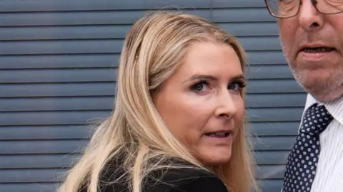 A blonde woman looking over her shoulder at the camera.