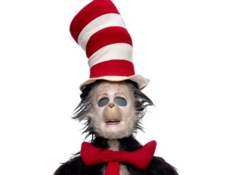 Propstore A screengrab of the original Cat in the Hat suit from the 2003 Mike Myers film, it features a tall red and white top hat and a red tie and is showing noticeable signs of disrepair. 