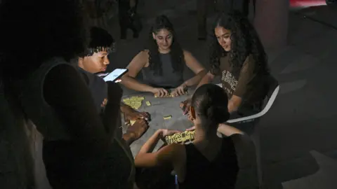 A group of people play dominoes in a street during a blackout in Havana