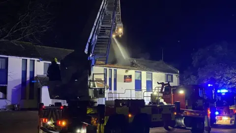 Firefighters and engines parked outside a white building after receiving reports of a fire