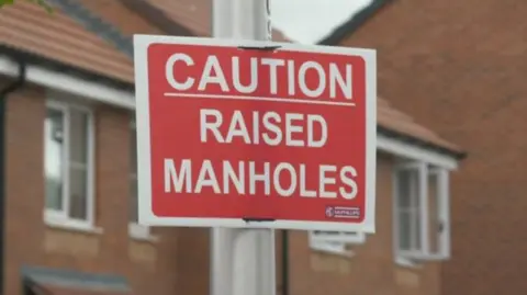 BBC News A Caution, Raised Manholes sign