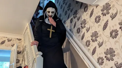 Mrs. Fisher's mother Ingrid in her ghostly nun costume comes down the stairs in the house