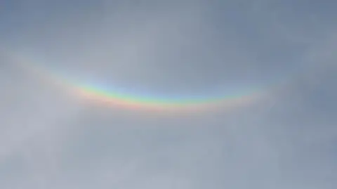 An upside down "rainbow" seen against a clear blue sky.