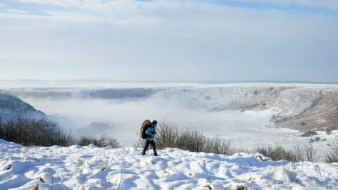 Danny Lawson A person walks through snow above the Hole of Horcum at the North York Moors National Park, as scattered weather warnings for snow and ice are in place across the UK as temperatures plunged below freezing overnight.