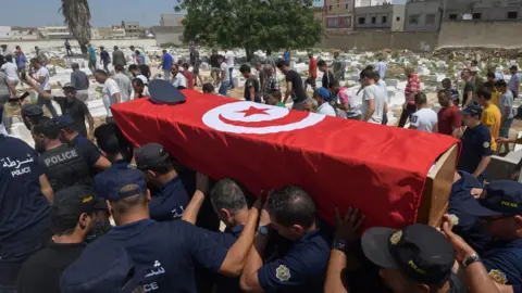 Empics Police officers carry the coffin of a fellow officer, who was killed in yesterday's suicide attack on Habib Bourguiba avenue, during his funeral in the Sidi Hassine western suburb of the capital Tunis on June 28, 2019. - Two blasts claimed by the Islamic State group killed a police officer in Tunis and wounded several other people on June 27, 2019.