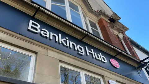 Link UK The outside of a building with a black sign with Banking Hub in white lettering
