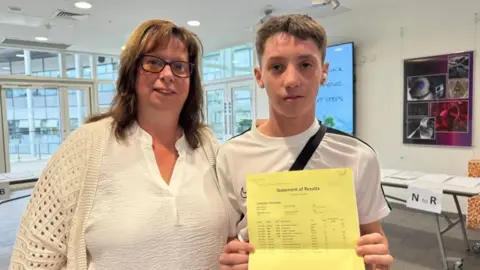 BBC/JO BURN A student holding his results alongside his mother. 