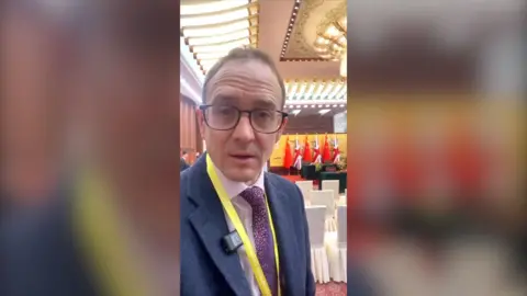 A man, Chris Mason, looking to camera in the Great Hall of the People