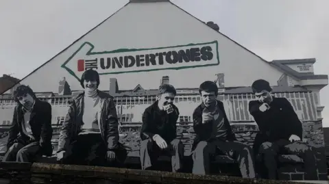 A mural on the wall of a house depicts the band, The Undertones, as they were on the cover of their debut album