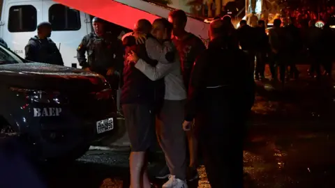 Getty Images Luiz Augusto de Oliveira (L), owner of the residence where the Voepass Airlines plane crashed, hugs people