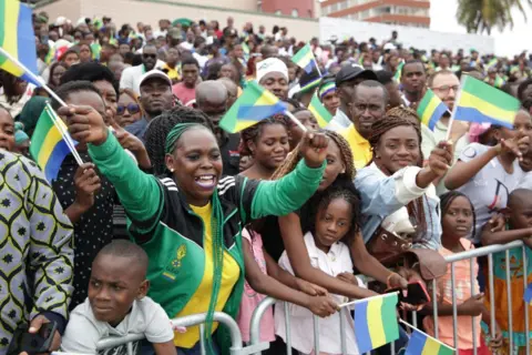 WILFRIED MBINAH / AFP Warga mengibarkan bendera selama parade militer untuk Hari Kemerdekaan Gabon.