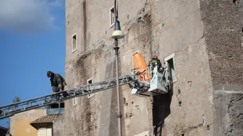 EPA A firefighter on a crane accesses a window in a stone building