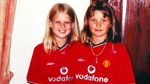 PA Media Jessica Chapman (left) and Holly Wells pictured wearing red Manchester United football shirts and smiling towards the camera